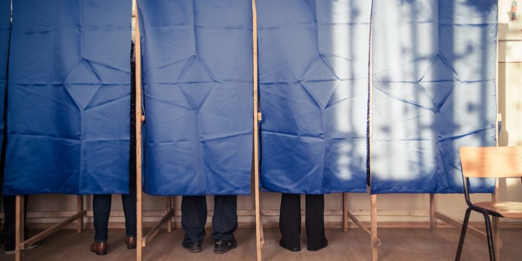 People vote in a voting booth at a polling station.